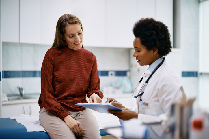 Happy woman going through her medical data with black female doctor at the clinic.