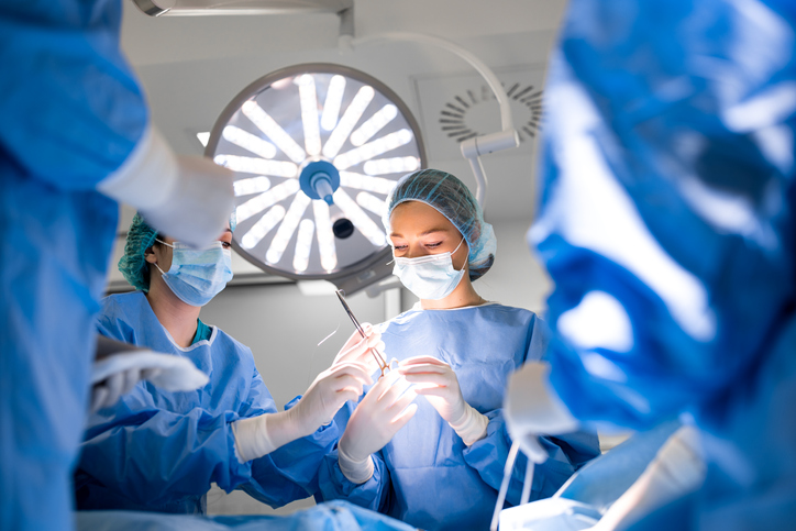 Team of professional doctors performing operation in surgery room. Medical Team Performing Surgical Operation in Bright Modern Operating Room