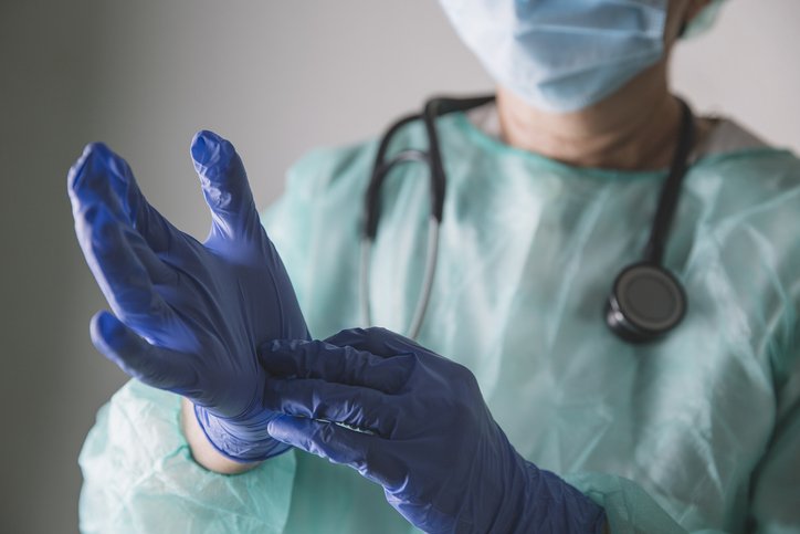 Medical worker putting on latex gloves